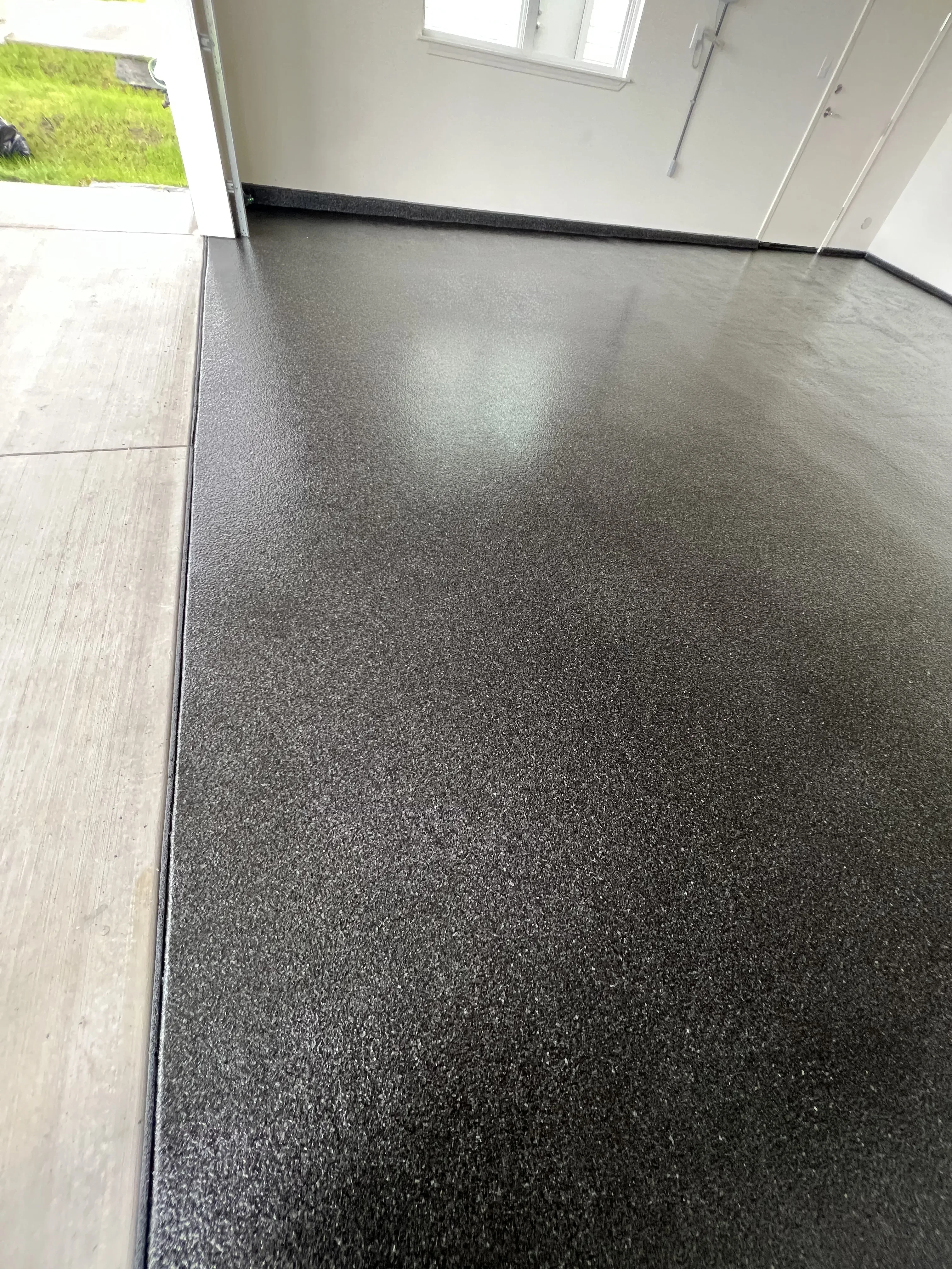 Dark gray epoxy floor with speckled finish and glossy coating installed in modern interior space