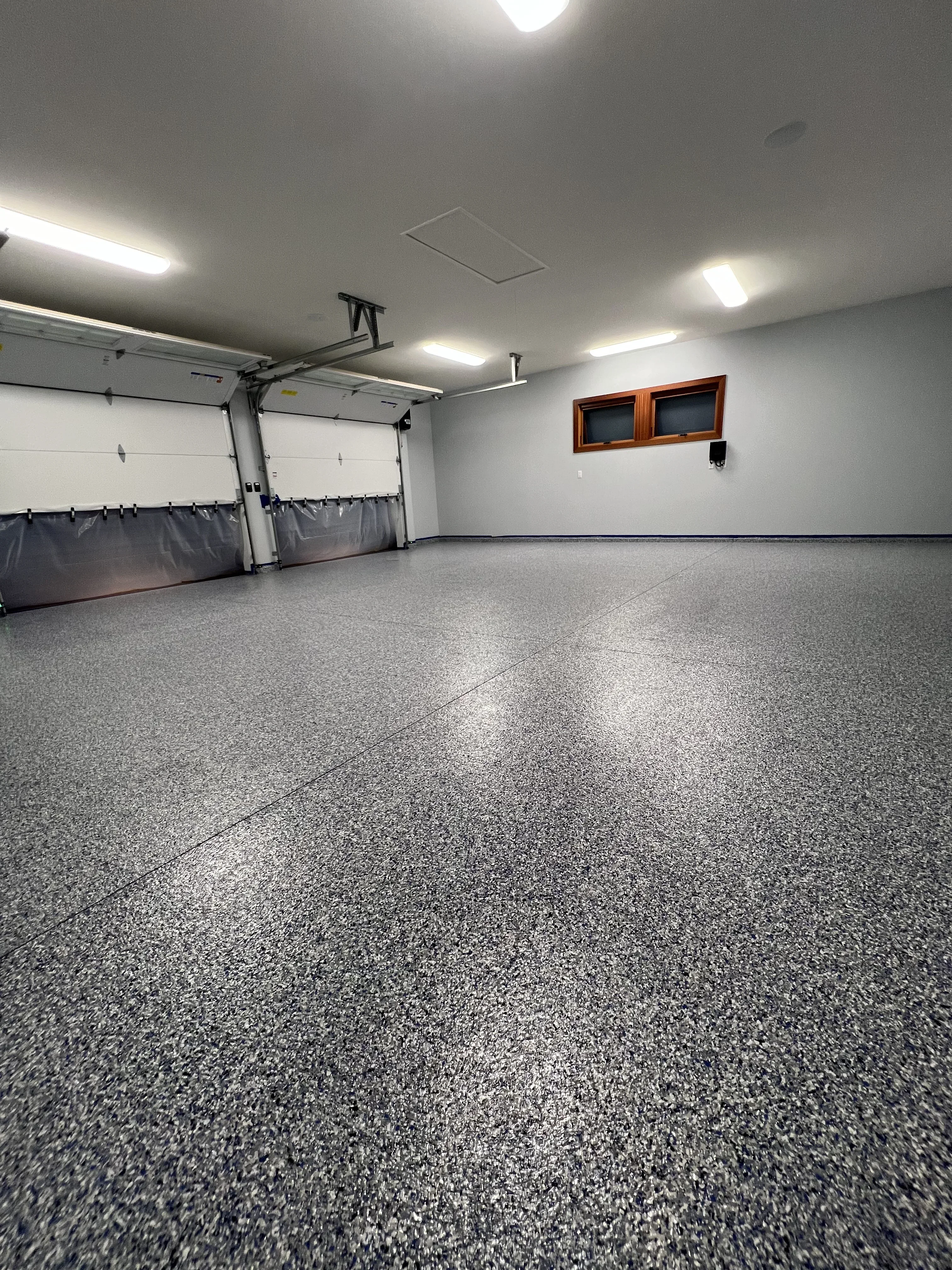 Finished epoxy garage floor with speckled gray coating and integrated LED lighting