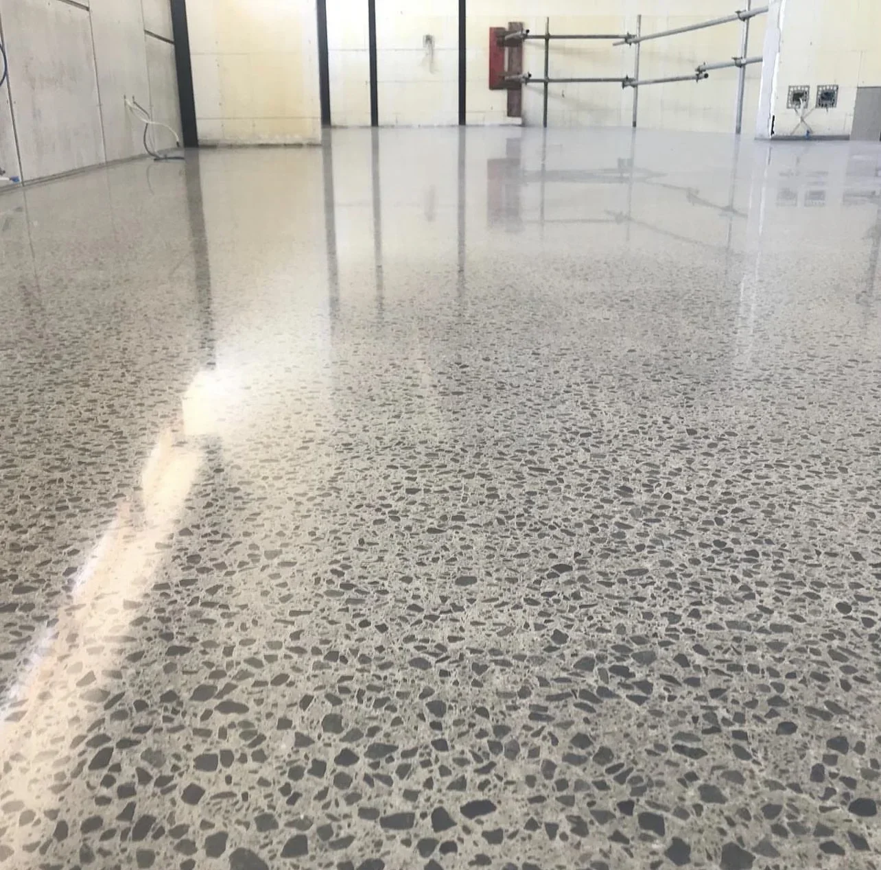 Polished concrete floor with reflective finish and exposed aggregate in industrial space