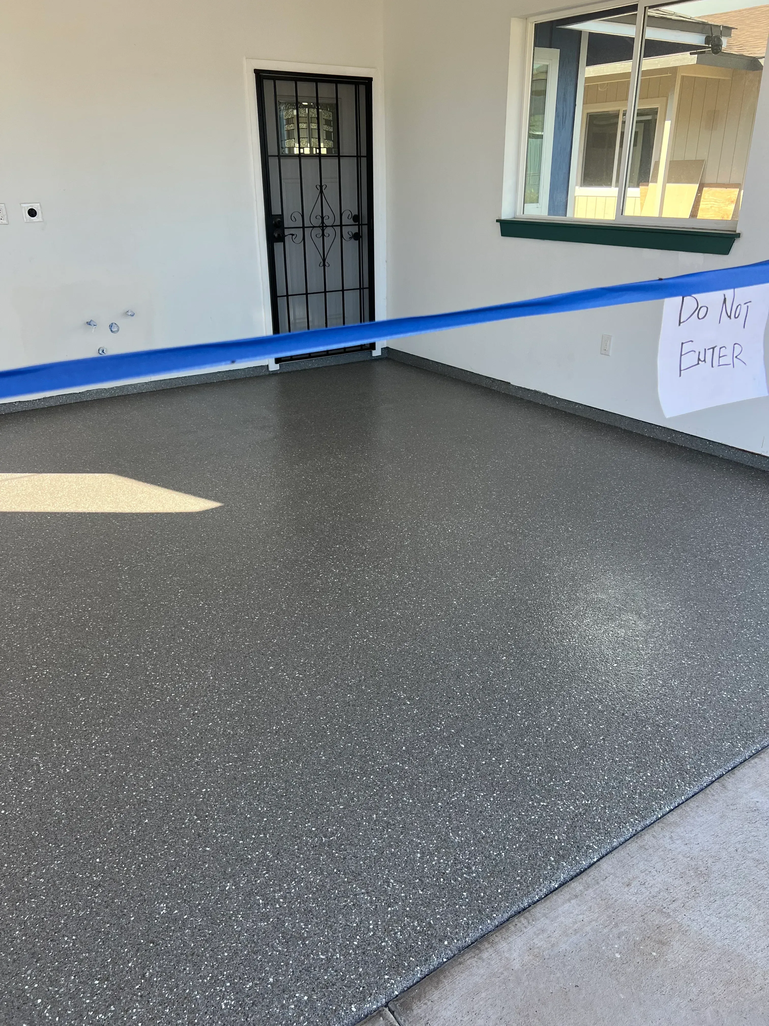 Newly installed gray epoxy garage floor with speckled finish and yellow center line