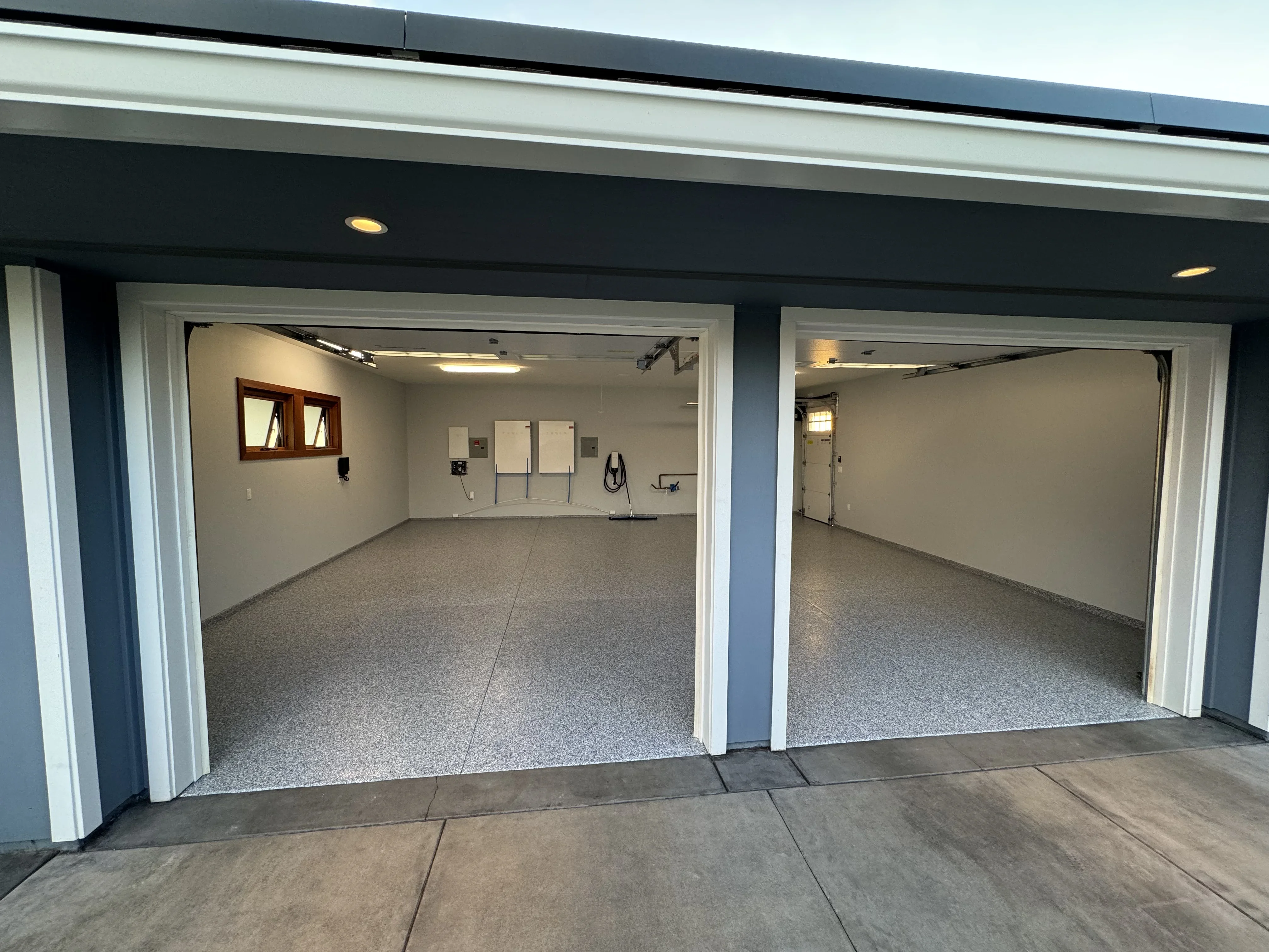 Two-bay garage with gray speckled epoxy flooring and white trim framing