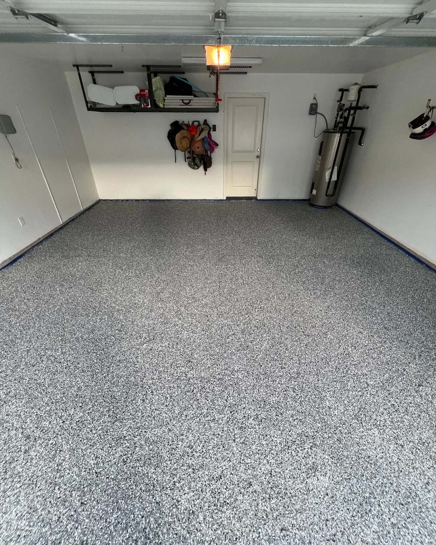 Gray speckled epoxy garage floor with blue border trim and organized storage