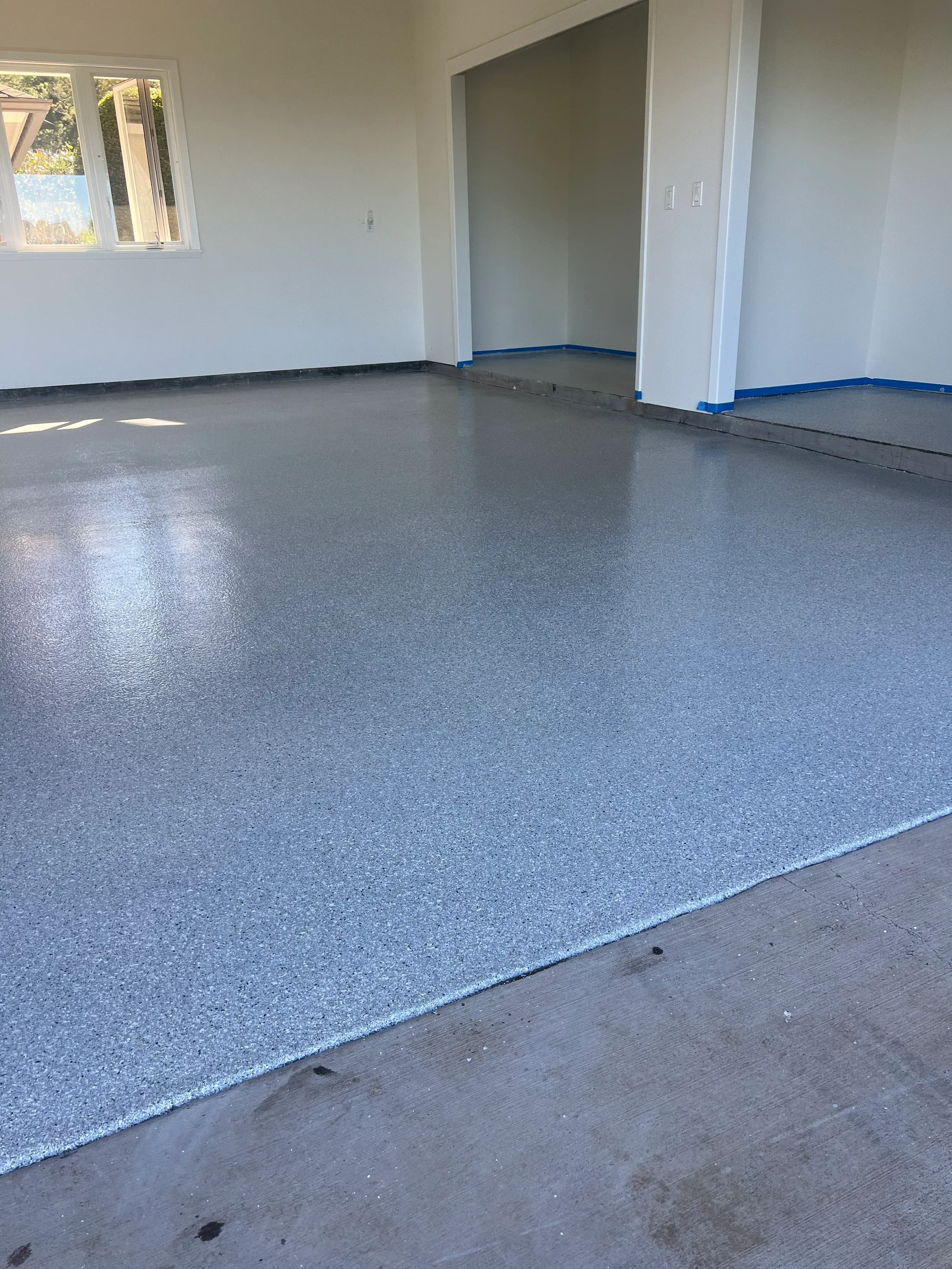 Newly installed light gray textured carpet with white transition trim and blue painter's tape marking installation boundaries